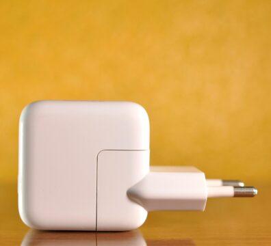 White power adapter against a warm, yellow background on a reflective surface.