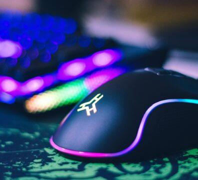 A close-up of a colorful gaming mouse and illuminated RGB keyboard, perfect for tech setups.