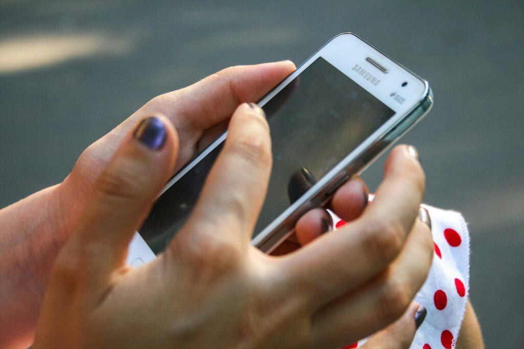 A woman interacts with a smartphone outdoors, focusing on connectivity and technology.