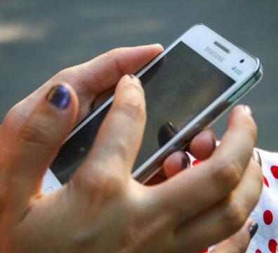 A woman interacts with a smartphone outdoors, focusing on connectivity and technology.