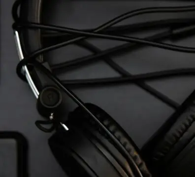 Black headphones and wallet on a dark surface, highlighting modern technology.