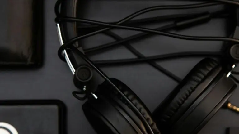 Black headphones and wallet on a dark surface, highlighting modern technology.