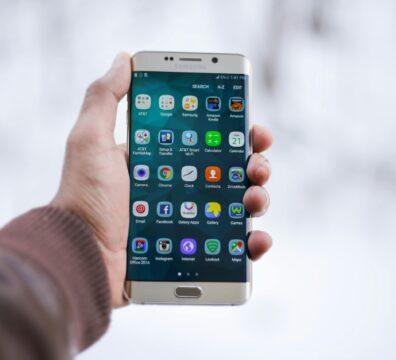 Close-up of a hand holding a Samsung smartphone displaying various app icons, emphasizing technology and connectivity.