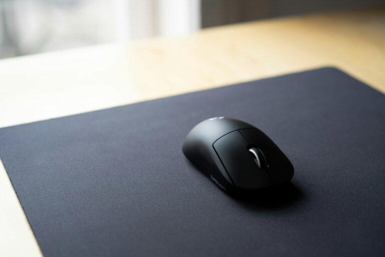 A sleek wireless computer mouse on a matte black mouse pad, perfect for an elegant workspace.